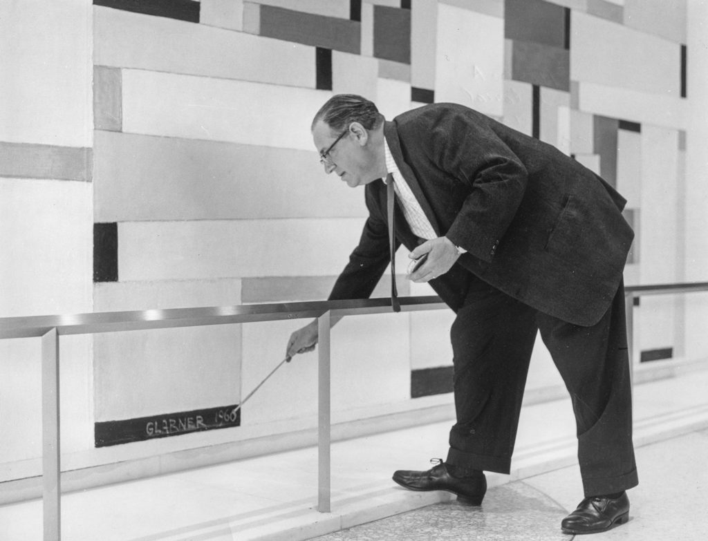 Photo of the artist Fritz Glarner signing his mural, "Relational Painting #88," 1960